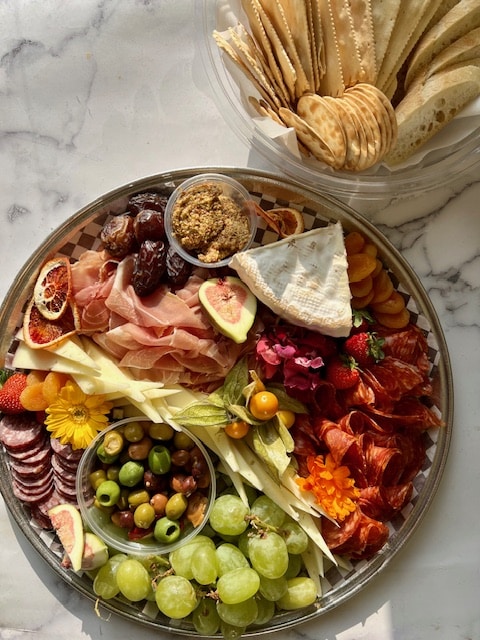 Charcuterie and cheese platter with olives, dips, grapes and crackers